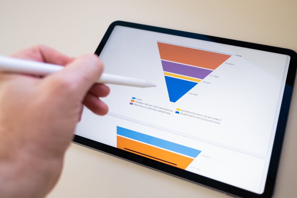 Sales marketing funnel showed on a tablet screen by a young marketer, sales manager pointing data with his pen.